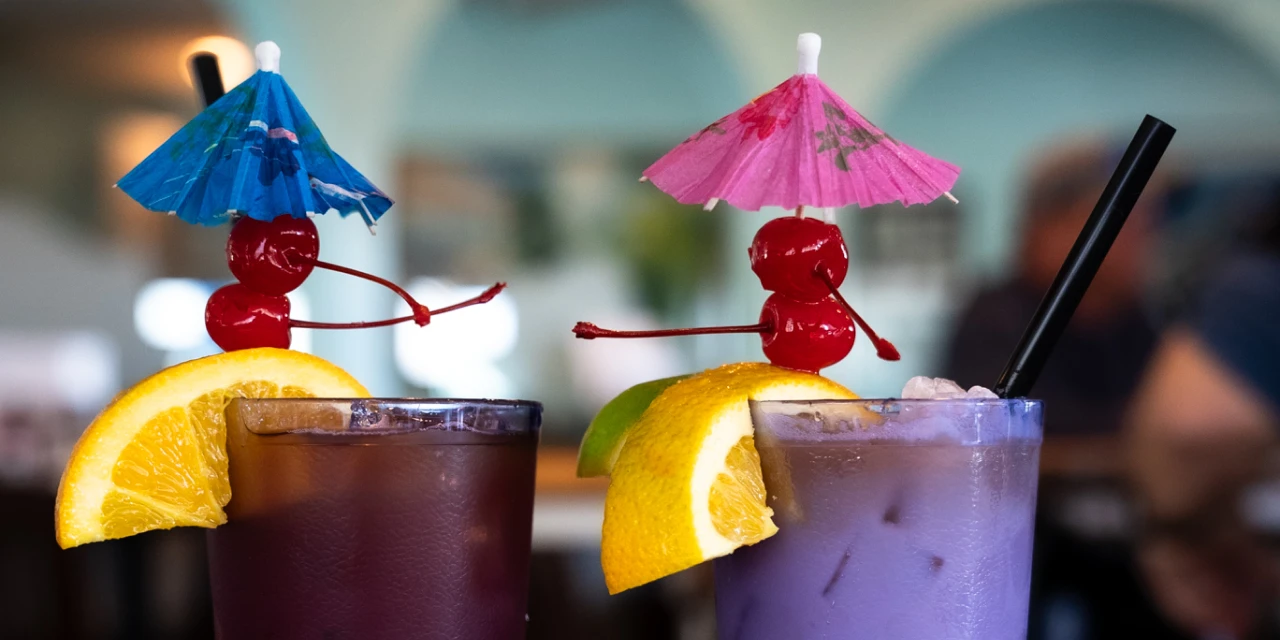 Two tropical cocktails with cherries, umbrellas, and fruit garnishes at Rum Bay Restaurant, a beachside resort bar on Palm Island, Florida.